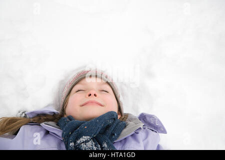 Girl lying on snow Banque D'Images