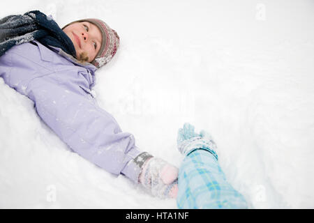 Girl lying on snow Banque D'Images