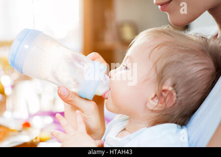 Un petit garçon est alimenté avec du lait d'une sucette par bouteille sa jeune mère. Banque D'Images