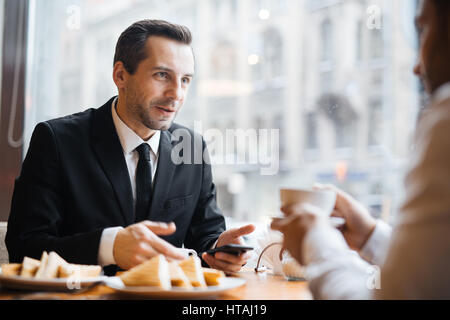 Portrait de deux hommes d'avoir chaud en discussion allumé cafe : brunette homme d'âge moyen de parler à un homme du bâti en gesticulant activement et sm Banque D'Images