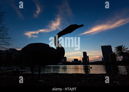 Un cygne est découpé par le coucher de soleil et vue sur l'horizon sur le Lac Eola à Orlando, Floride. Lake Eola Park est situé au cœur du centre-ville d'Orlando et d'accueil à l'Amphithéâtre de Walt Disney. Banque D'Images