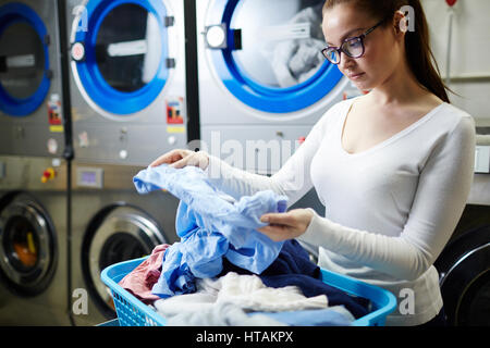 Woman looking at dirty shirt de la blanchisserie Banque D'Images