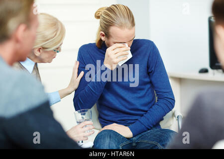 Portrait de jeune homme assis en cercle de soutien psychologique de pleurer tout en partageant son groupe avec le mentor et les autres participants Banque D'Images