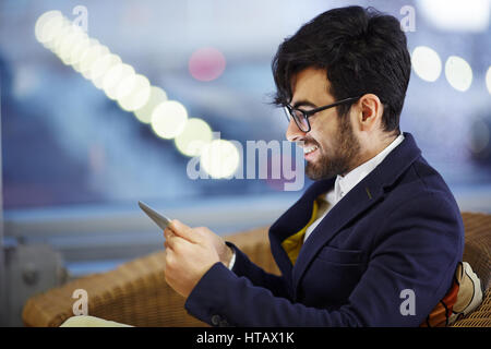 Side view portrait of young handsome middle eastern woman fauteuil en cuir à l'aide de smartphones reading text message Banque D'Images