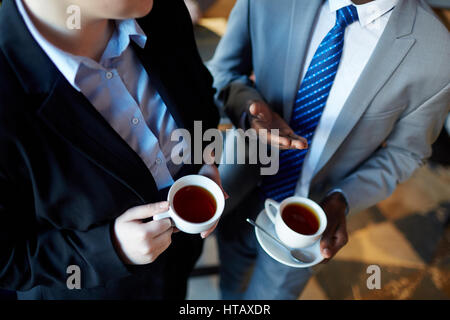 High angle de deux personnes qui interagissent au cours de pause café : méconnaissable portrait à collègue gesticulant et tenant des tasses avec plateau Banque D'Images