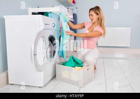 Jeune femme à la recherche de vêtements après le lavage en machine à laver à la Buanderie Banque D'Images