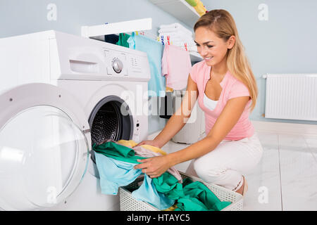 Chargement femme vêtements sales dans la machine à laver pour laver dans buanderie Banque D'Images