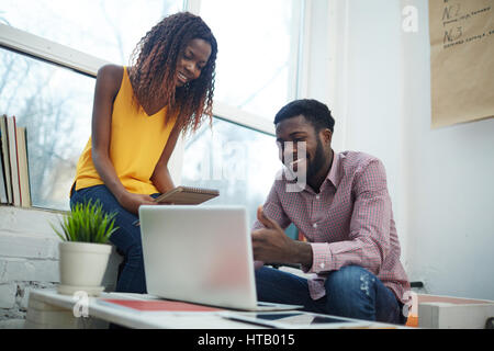 Jeune femme à la recherche à la présentation de sa collègue ou groupmate Banque D'Images