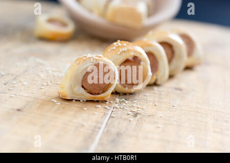 Les porcs fait maison dans une couverture. Saucisses roulées dans un croissant au four pâte sur rack de refroidissement du métal au sésame. Selective focus Banque D'Images