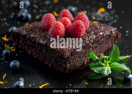 Gâteau au chocolat avec des framboises, bleuets, le zeste d'orange et pipermint Banque D'Images