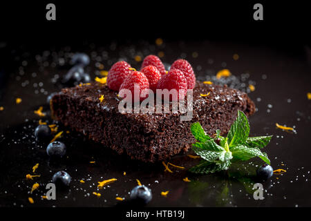 Gâteau au chocolat avec des framboises, bleuets, le zeste d'orange et pipermint Banque D'Images