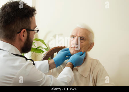 Le médecin examine les ganglions sur le cou d'une vieille femme. Banque D'Images