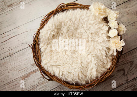 Vider le panier rempli d'un tapis flokati et de fleurs sur le bord du panier. Utilisé par un photographe pour nouveau-né Banque D'Images