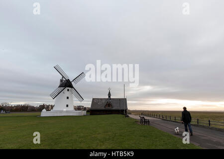 Lytham Windmill est situé sur Lytham vert dans la ville côtière de Lytham St Annes, Lancashire, Angleterre. Un homme promène son chien au lever du soleil Banque D'Images