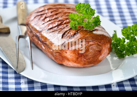 Pain de viande bavarois sur une assiette blanche servi sur une table avec une nappe à carreaux bleu et blanc Banque D'Images