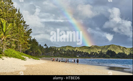 Kailua, Hawaii, USA - 30 juillet 2016 : des personnes non identifiées, recueillir et marcher le long de la plage de sable rives de Kailua Bay avec un arc-en-ciel au-dessus. Banque D'Images