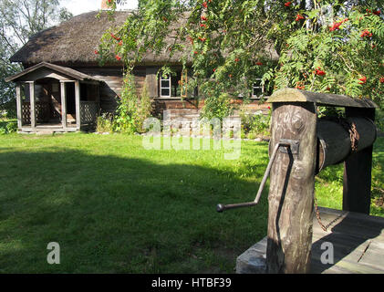Un chalet en bois traditionnel et bien avec un arbre dans la campagne lettone. Banque D'Images