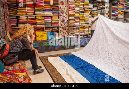 Une femme assise et une vue sur les textiles d'être illustré par un vendeur dans un show room, Jodhpur, Rajasthan, Inde. Banque D'Images