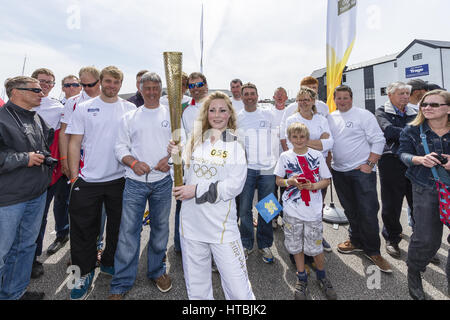 Un porteur de flambeau olympique 2012 pose avec l'équipe de voile Finn pendant la Flamme Olympique sur la main relais en Falmouth Banque D'Images