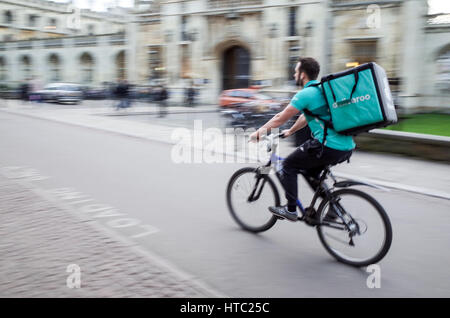 Un Deliveroo tirets par courier alimentaire Centre de Cambridge UK (flou de mouvement) Banque D'Images