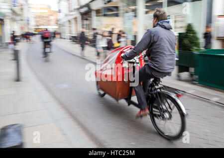 Les parents transportent leurs enfants de l'école dans les vélos-cargos dans le centre de Cambridge Banque D'Images