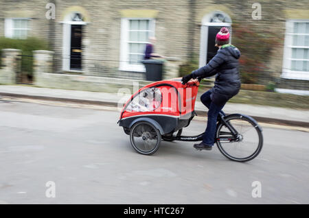 Les parents transportent leurs enfants de l'école dans les vélos-cargos dans le centre de Cambridge Banque D'Images