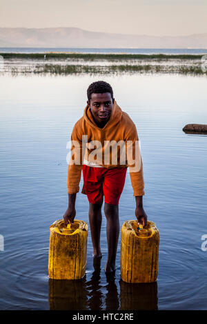 Un adolescent recueille l'eau du lac dans des conteneurs, le lac Awassa, Ethiopie Banque D'Images