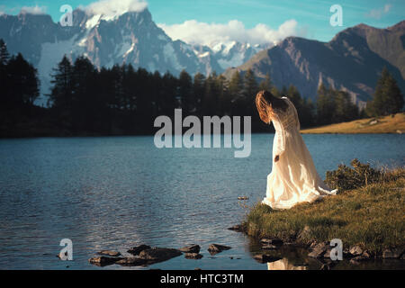 Woman posing in Mountain Lake au coucher du soleil. Rêveur et romantique Banque D'Images