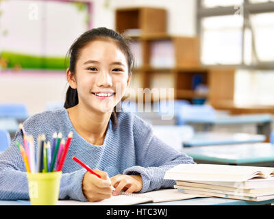 Happy asian elementary school student studying in classroom, smiling at camera Banque D'Images