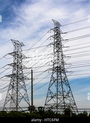 Un des pylônes d'électricité à haute tension contre le ciel bleu et rayons de soleil Banque D'Images