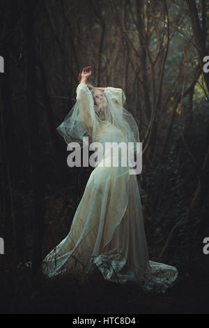 Triste mariée avec voile dans la forêt. Surréaliste et sombre Banque D'Images