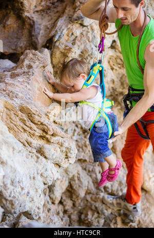 Rock climber aider sa fille dans le harnais de sécurité à tenir sur la falaise Banque D'Images