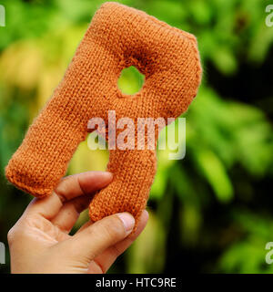 La main femme alphabet tricotés sur la nature de fond vert, la couleur du produit à partir de fils tricotés à la main avec creative Banque D'Images