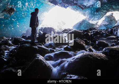 Un homme se tient sur un rocher à l'intérieur d'une grotte de glace sous le glacier en racine Wrangell-St. Elias National Park, Southcentral Alaska, USA Banque D'Images