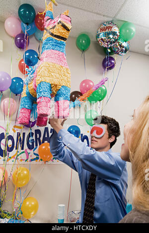 Les employés de bureau à jouer avec une piñata Banque D'Images