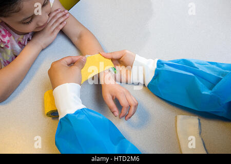 Girl infirmière mettre bandage sur son bras Banque D'Images