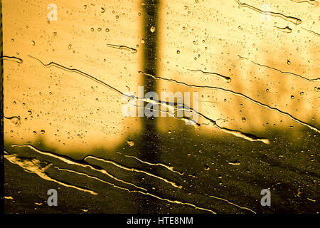 Gouttes glissant sur une fenêtre d'un train en mouvement rapide sur le coucher du soleil Banque D'Images