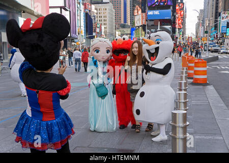 Un touristes asiatiques pose pour des photos avec des artistes habillés comme des personnages de bande dessinée et de la télévision. Times Square, New York City. Banque D'Images