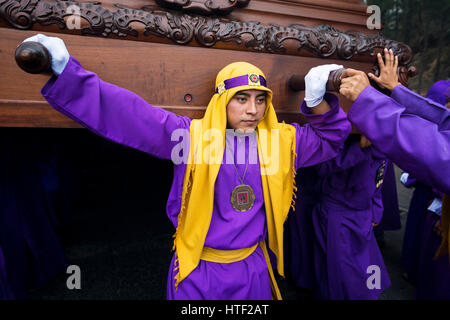 Antigua, Guatemala - 16 Avril 2014 : Man wearing robes pourpres, transportant un flotteur (ANDA) au cours de la célébration des fêtes de Pâques, dans la Semaine Sainte, à Antigua, G Banque D'Images