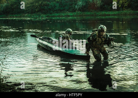 L'atterrissage clandestines. Paire d'opérateurs armés avec des visages peints de débarquement de la côte de la rivière kayak militaire . Mission de diversion sous le couvert de l'obscurité Banque D'Images