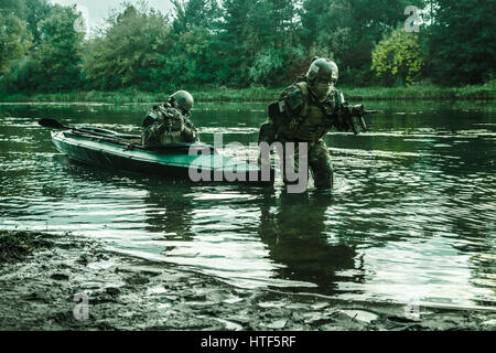 L'atterrissage clandestines. Paire d'opérateurs armés avec des visages peints de débarquement de la côte de la rivière kayak militaire . Mission de diversion sous le couvert de l'obscurité Banque D'Images