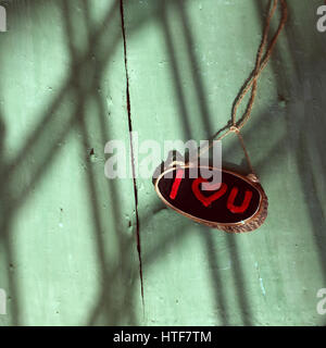 Je t'aime lettre de couleur rouge sur le bandeau noir et vert fond bois, un message romantique pour couple, nuances de la lumière du soleil sur le bois en font impression Banque D'Images