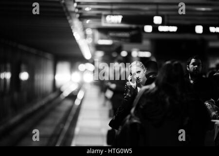 Femme debout parmi les usagers du métro à parler sur son téléphone cellulaire. Banque D'Images
