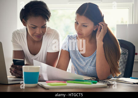 Deux femmes entrepreneurs qui travaillent ensemble dans le bureau de discuter d'une feuille de calcul avec des statistiques à un bureau , low angle view Banque D'Images