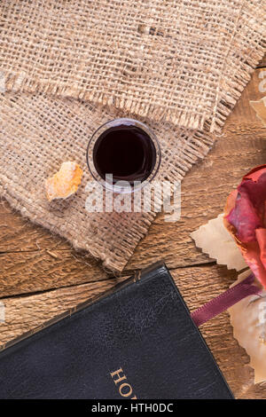 Prendre la communion. Tasse de verre avec du vin rouge, du pain et de la Sainte Bible sur table en bois close-up Banque D'Images