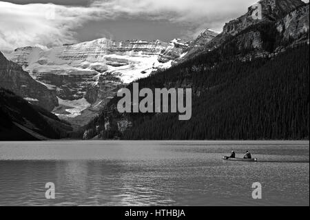 Canoë sur le lac Louise, Alberta, Canada, en N&B avec des Montagnes Rocheuses couvertes de neige qui englobe le lac. Un glacier de vallée est au-delà du lac Banque D'Images