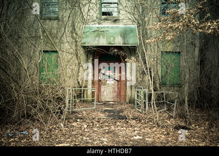 Vue de l'extérieur de l'hôpital psychiatrique abandonné avec de l'amiante sur la porte d'avertissement Banque D'Images