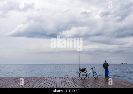 Pêcheur dans le front de mer de Thessalonique, Grèce, sous un ciel nuageux Banque D'Images