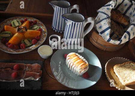 Agréablement agencé plateau de petit-déjeuner composé de croissants et du pain, des tomates et du fromage, jambon ibérique, beurre, confiture, gâteaux, fruits, du café et du lait. Banque D'Images