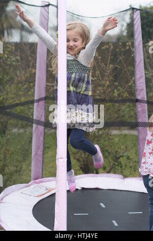 Heureux plaisir blondes, les enfants, les enfants jouant à très heureux de rire et sourire de sauter sur un trampoline dans le jardin Banque D'Images